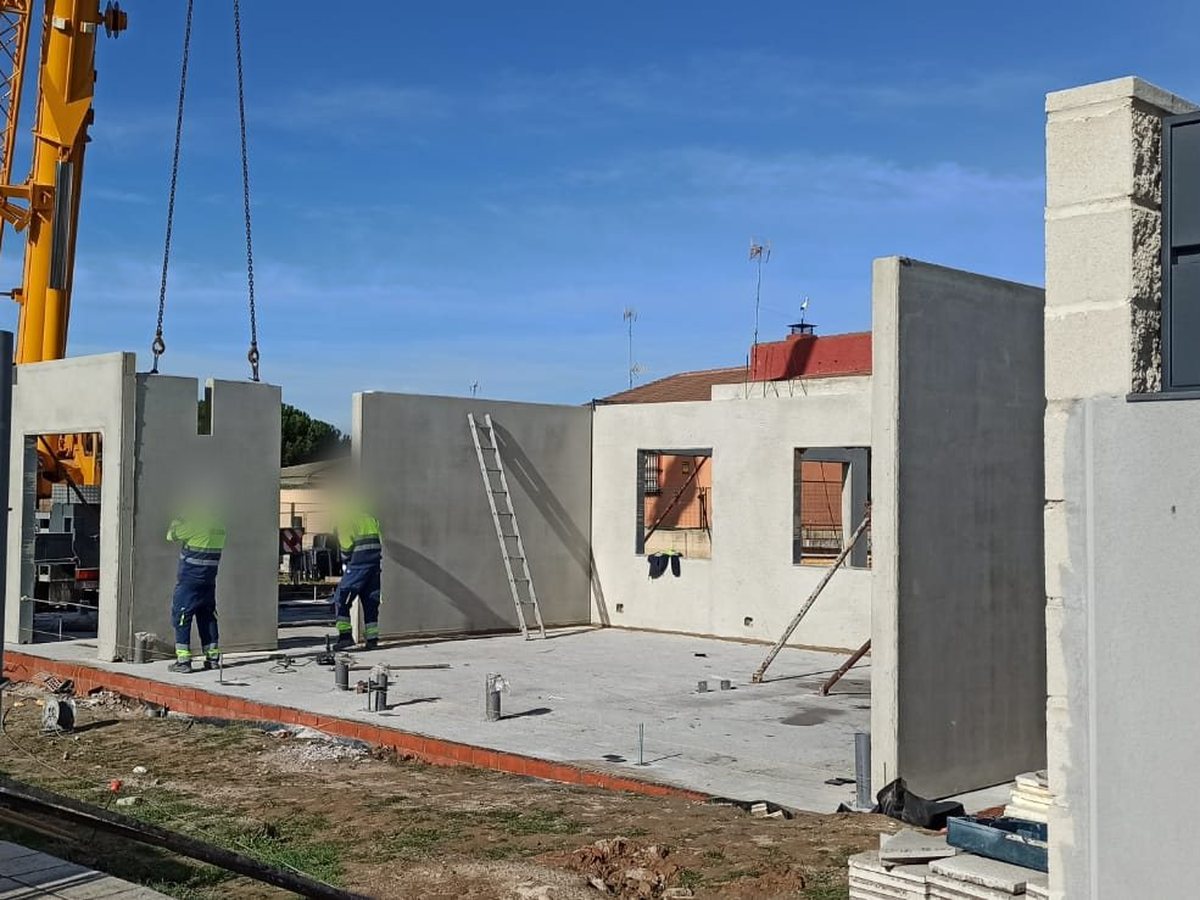 Grúa colocando los paneles de hormigón prefabricado sobre la solera de la vivienda