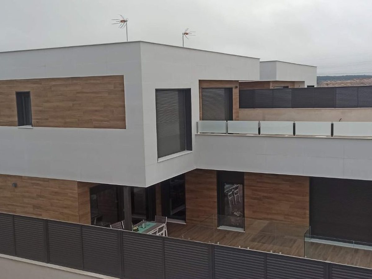 La misma promoción terminada: volúmenes blancos con fachada ventilada de madera y carpintería oscura