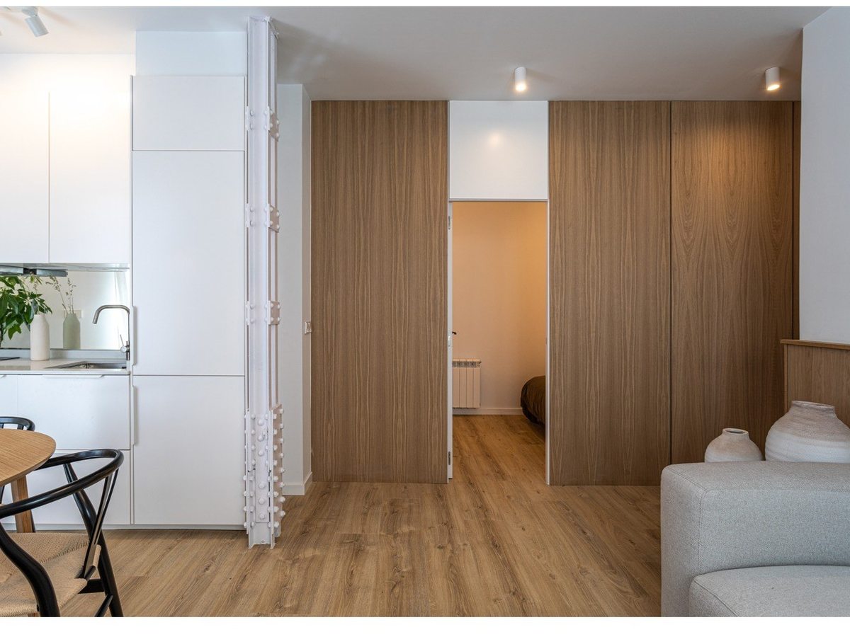 La misma vivienda terminada: cocina abierta al salón, suelo nuevo y frente de madera