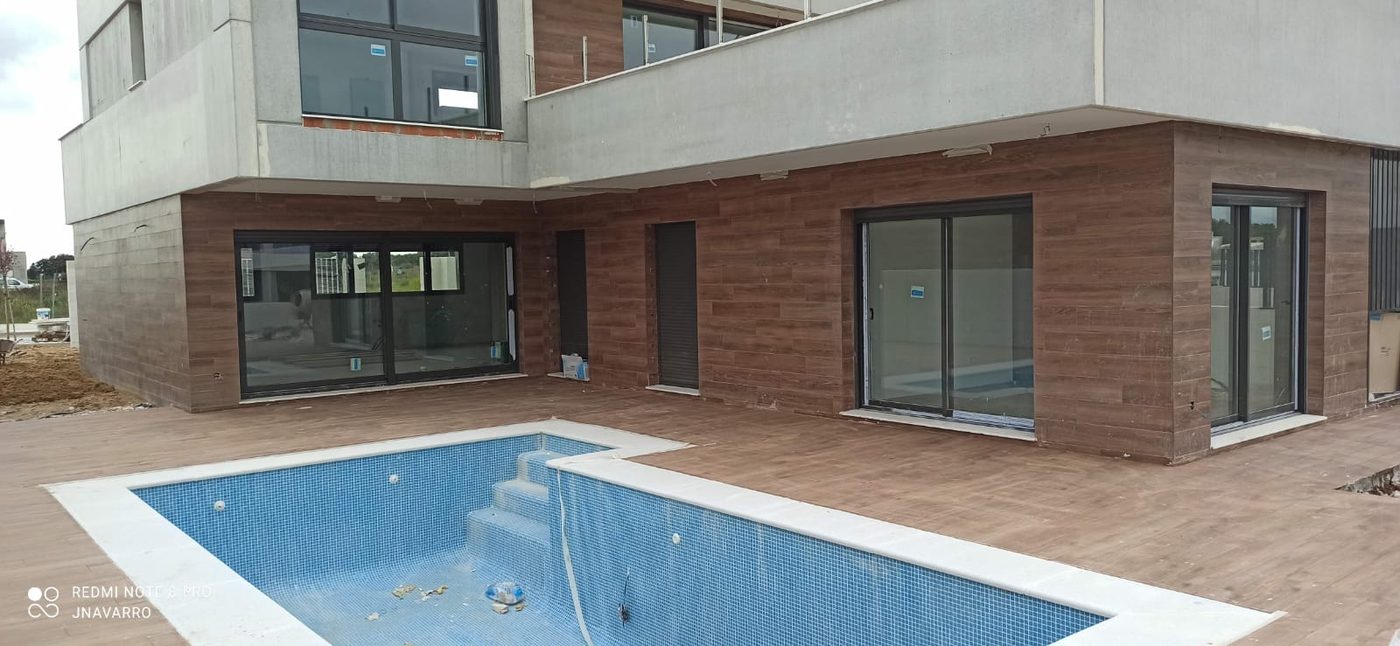 Vivienda de hormigón prefabricado terminada, con piscina y fachada ventilada de madera