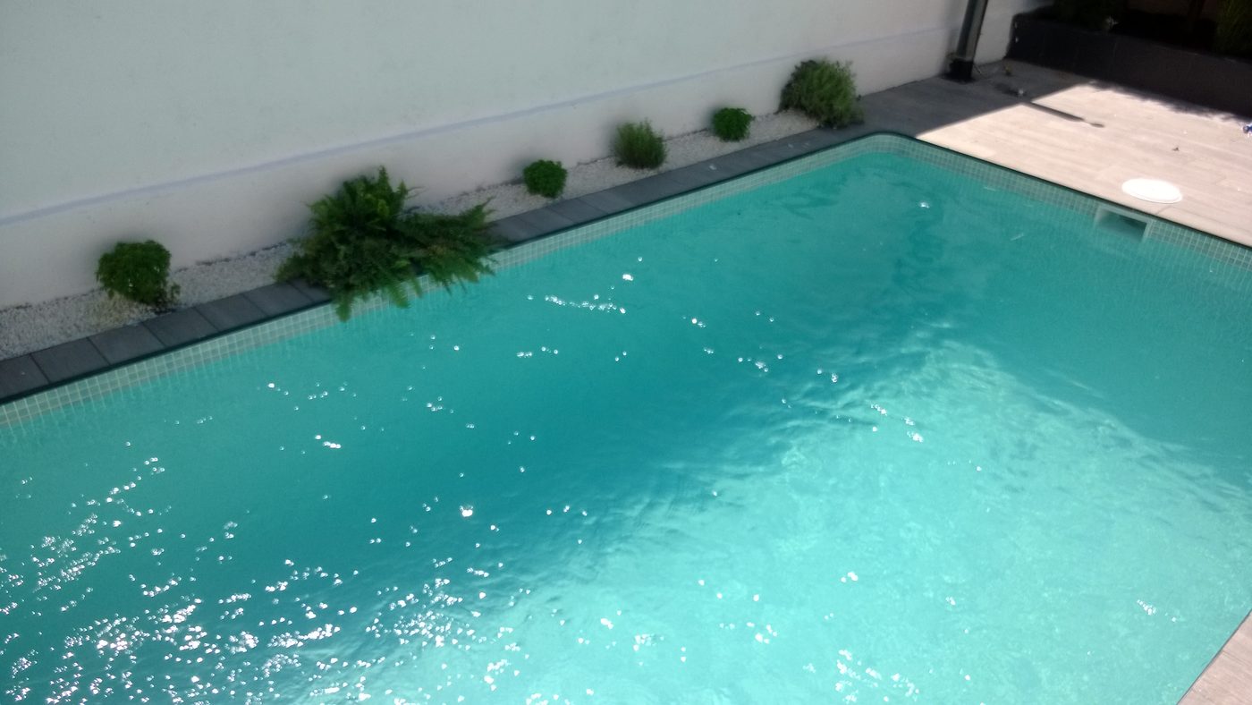 Piscina terminada y llena, con borde de piedra y solado perimetral