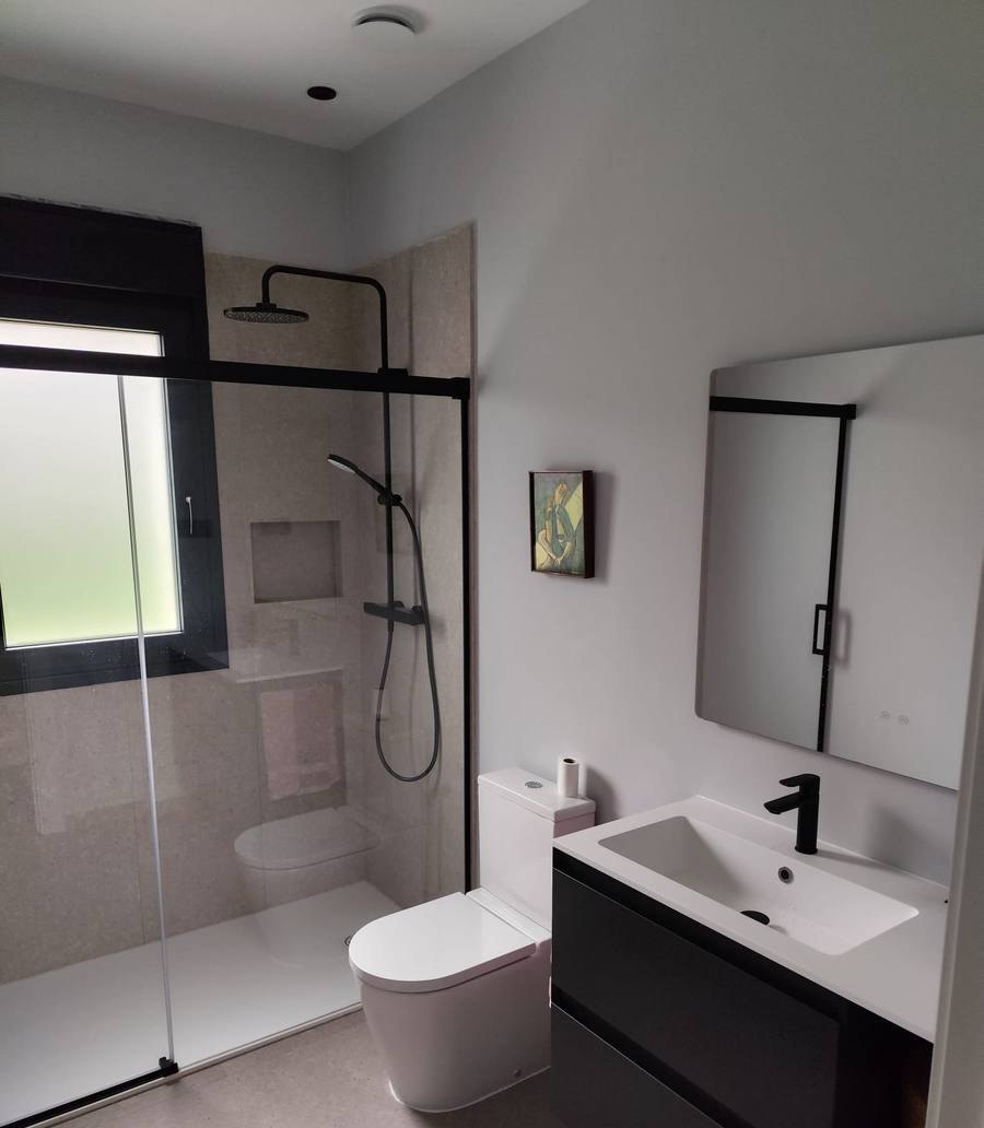 Baño terminado con plato de ducha enrasado, mampara de cristal y mueble suspendido