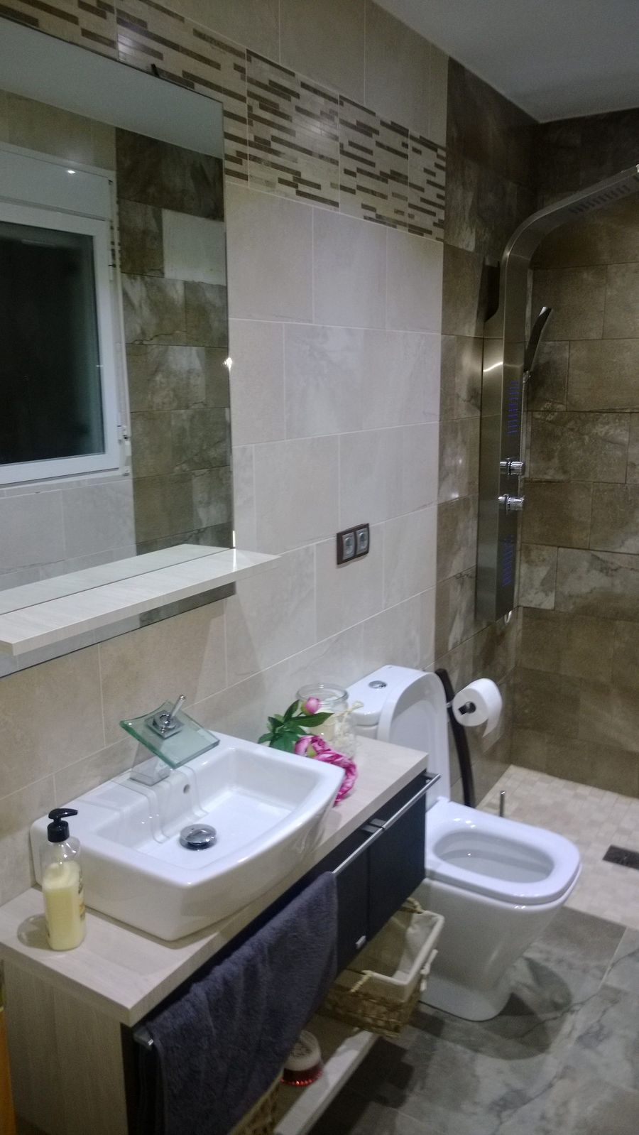 Baño terminado con doble lavabo sobre mueble oscuro, ducha alicatada y encimera de piedra
