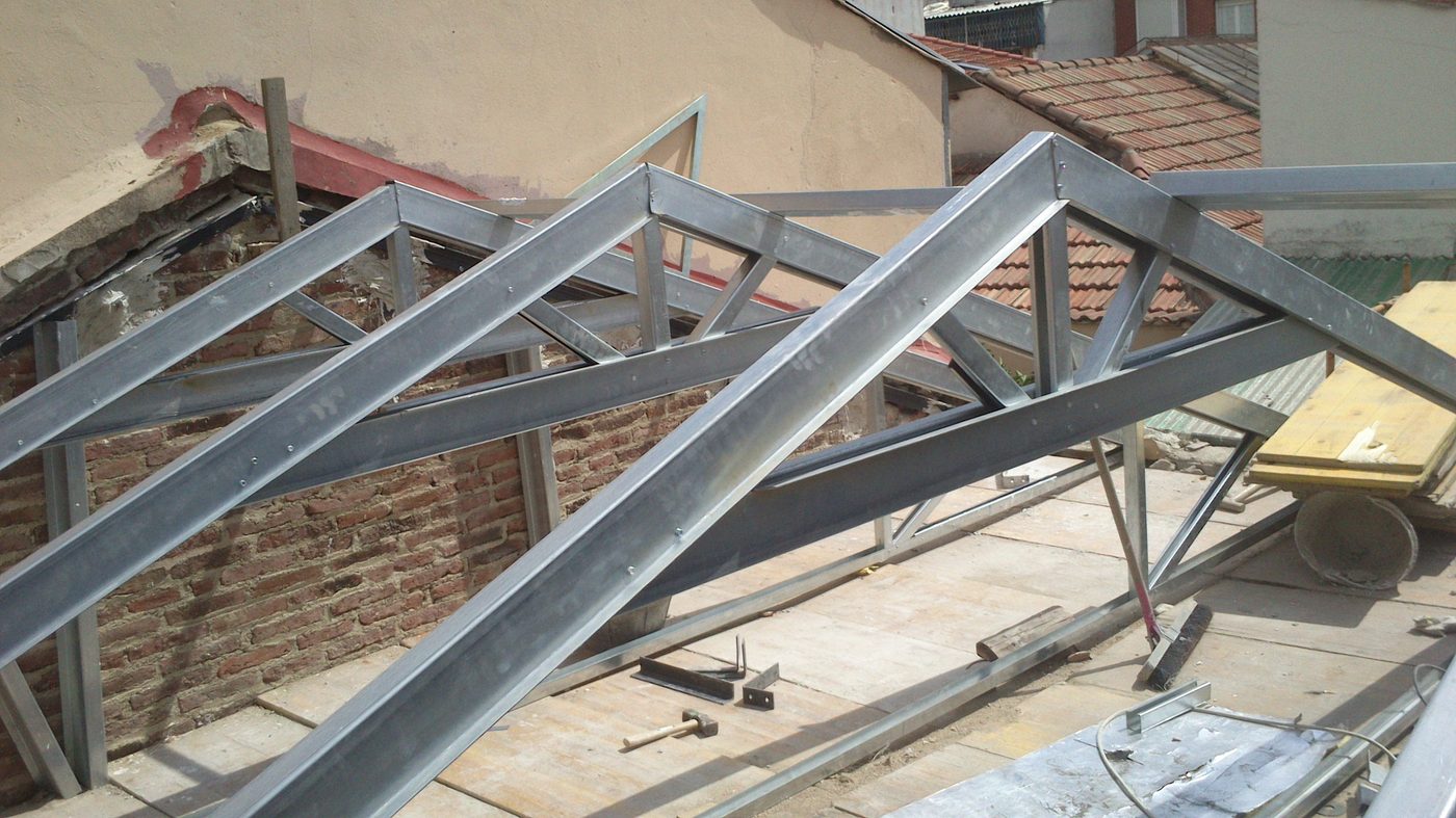Estructura metálica de una cubierta en ejecución, con las cerchas montadas sobre el muro de fábrica