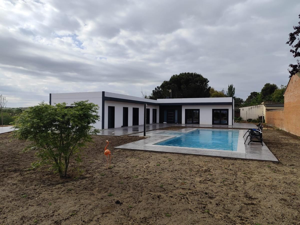 Chalet de una planta con cubierta plana y piscina, visto desde el jardín, obra de Waldina